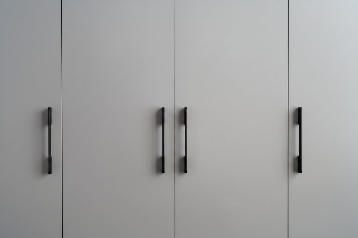 Two black vertical cabinet handles mounted on light gray double doors.